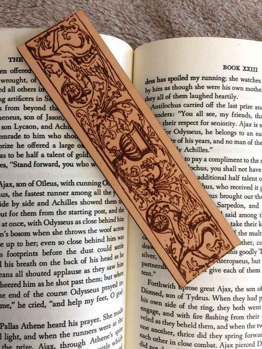 A leather bookmark engraved with the antique art of a cherub angels riding a hippocampus.