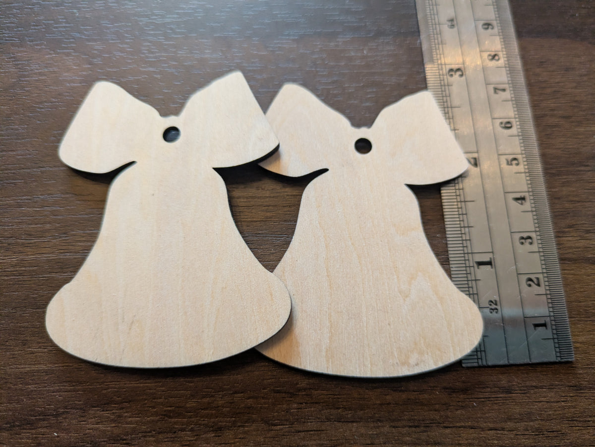 A photograph of the wooden Christmas bell ornament blanks next to a ruler for scale.