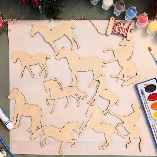 A photograph of set 1 for the horse ornament shapes. Set 1 includes 10 horse and mule wood cutouts. In the photograph is also paint and water colors which you can add to make a full horse ornament kit.