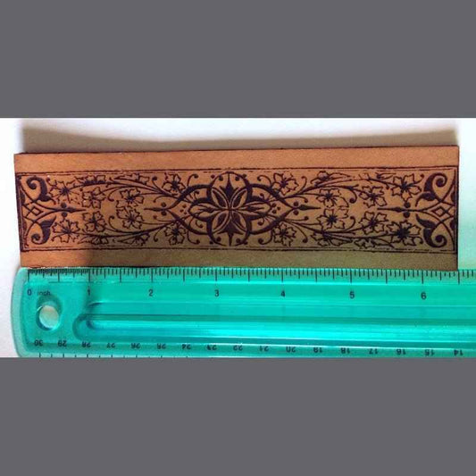 Leather bookmark with a decorative historical floral and iron design engraved on it.