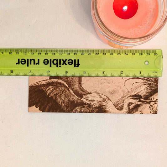 A photograph of the heron with a frog bookmark next to a ruler for scale. Heron with a Frog Bookmark - Leather Historical Bookmarks Raven King Crafts