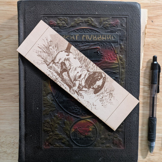 A rectangular leather bookmark with the historical art of a basset hound dog engraved on it. Leather Basset Hound Bookmark Bookmarks Raven King Crafts