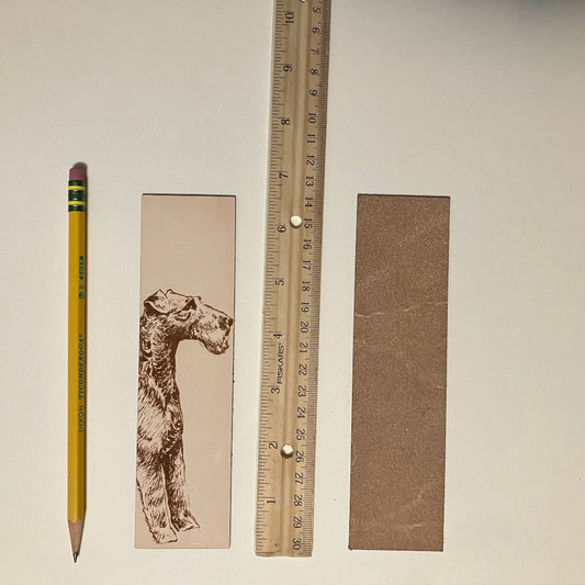 The leather Irish Terrier bookmark next to a ruler and a pencil to show scale. Also the back of the bookmark is unfinished. Leather Irish Terrier Bookmark Bookmarks Raven King Crafts