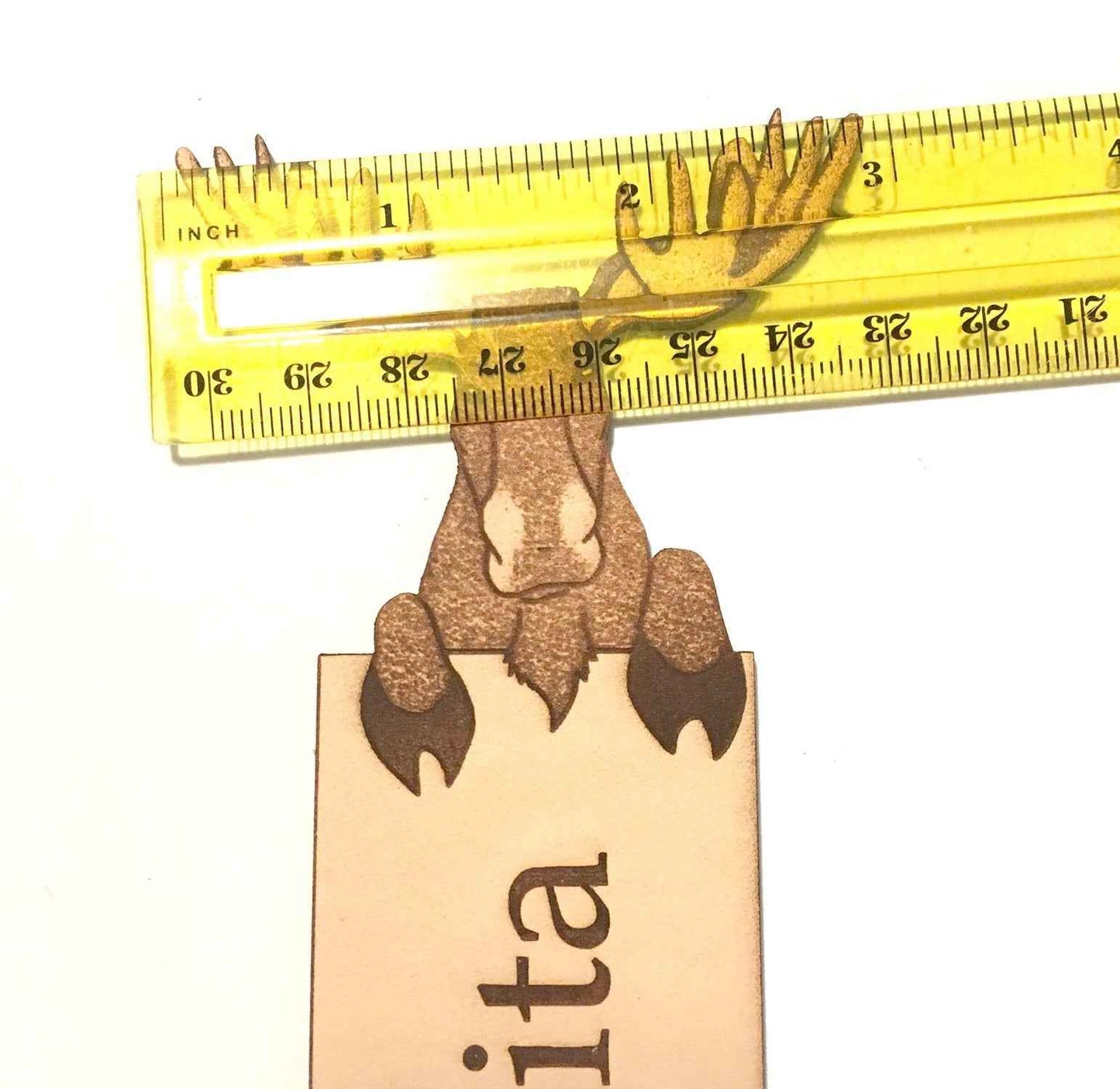 A photograph of exclusive personalizable moose leather bookmark next to a ruler for scale.