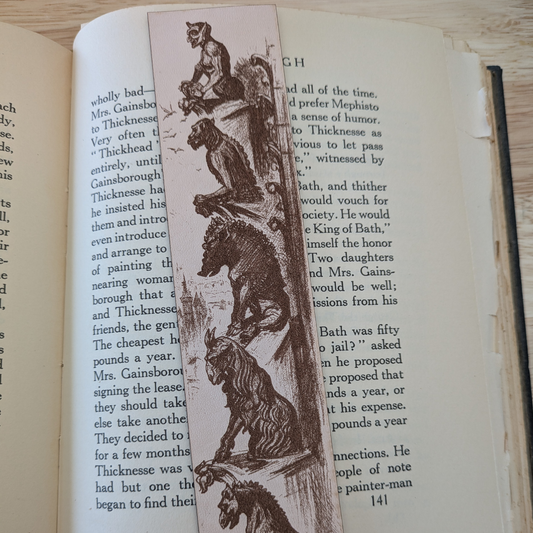 A leather bookmark engraved with the historical art of a collection of gargoyles.