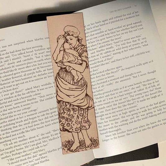 A leather bookmark engraved with the antique art of a mother and child.