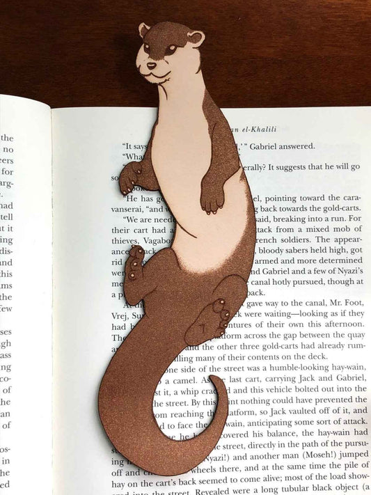 Leather otter shaped bookmark on the pages of an open book.