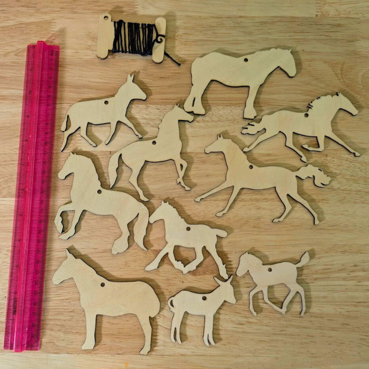 Set 2 of the wooden horse ornament sets next to a ruler to show scale. The set has 10 different horse, mule and donkey cutouts.