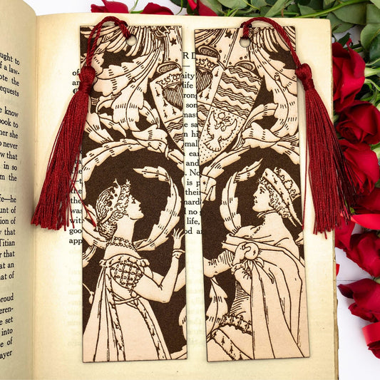 A set of historical bookmarks, a woman in a fine dress is on the left and the right one is a man with a cape and hat. This couple bookmark set has tassels and you can pick the colors, the photo here shows the wine red option.