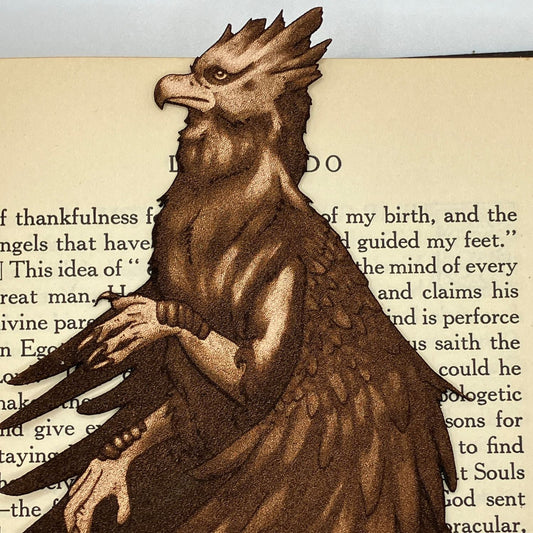 A leather hippogriff bookmark resting on the pages of a book.