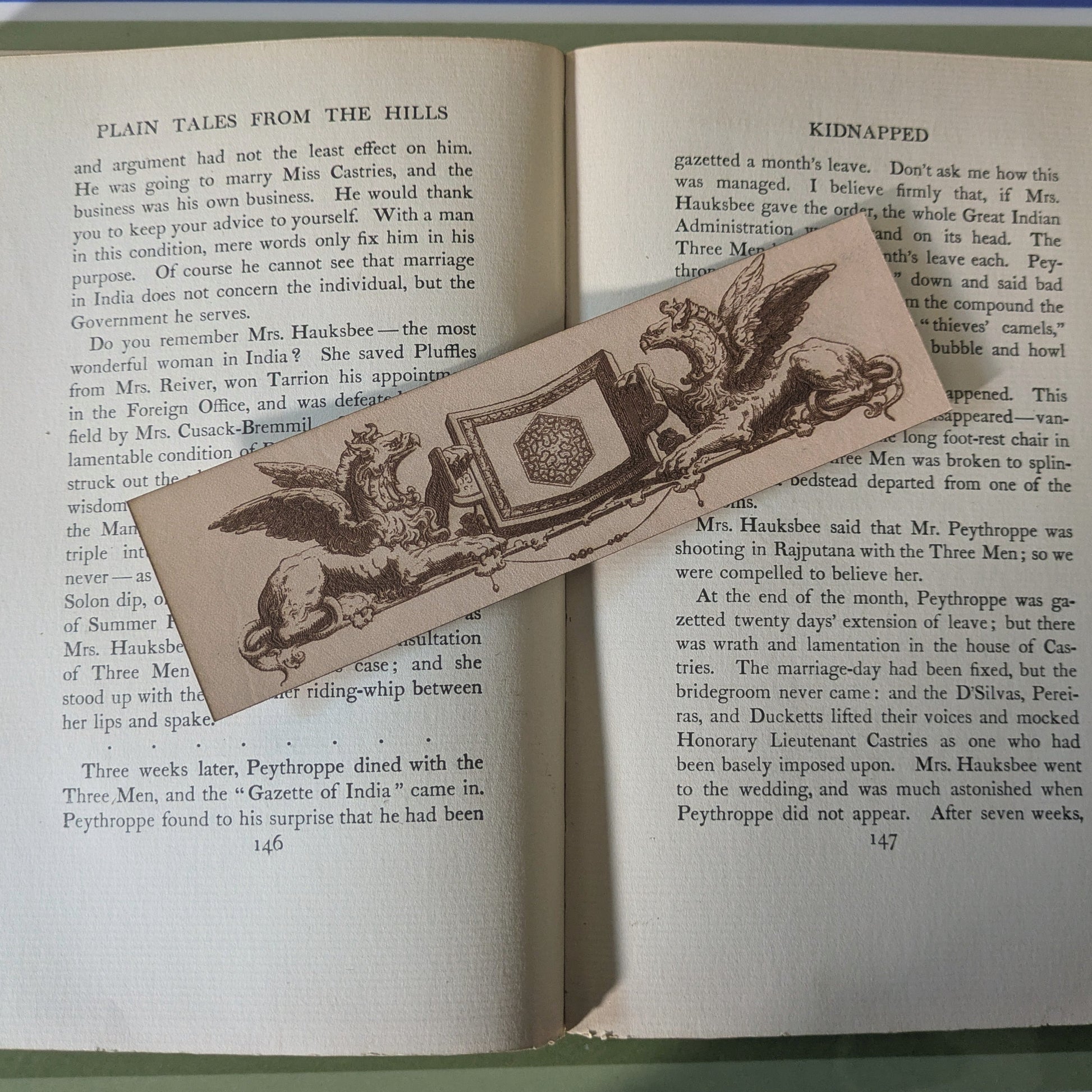 A leather bookmark with the art of 2 griffins holding a shield. 