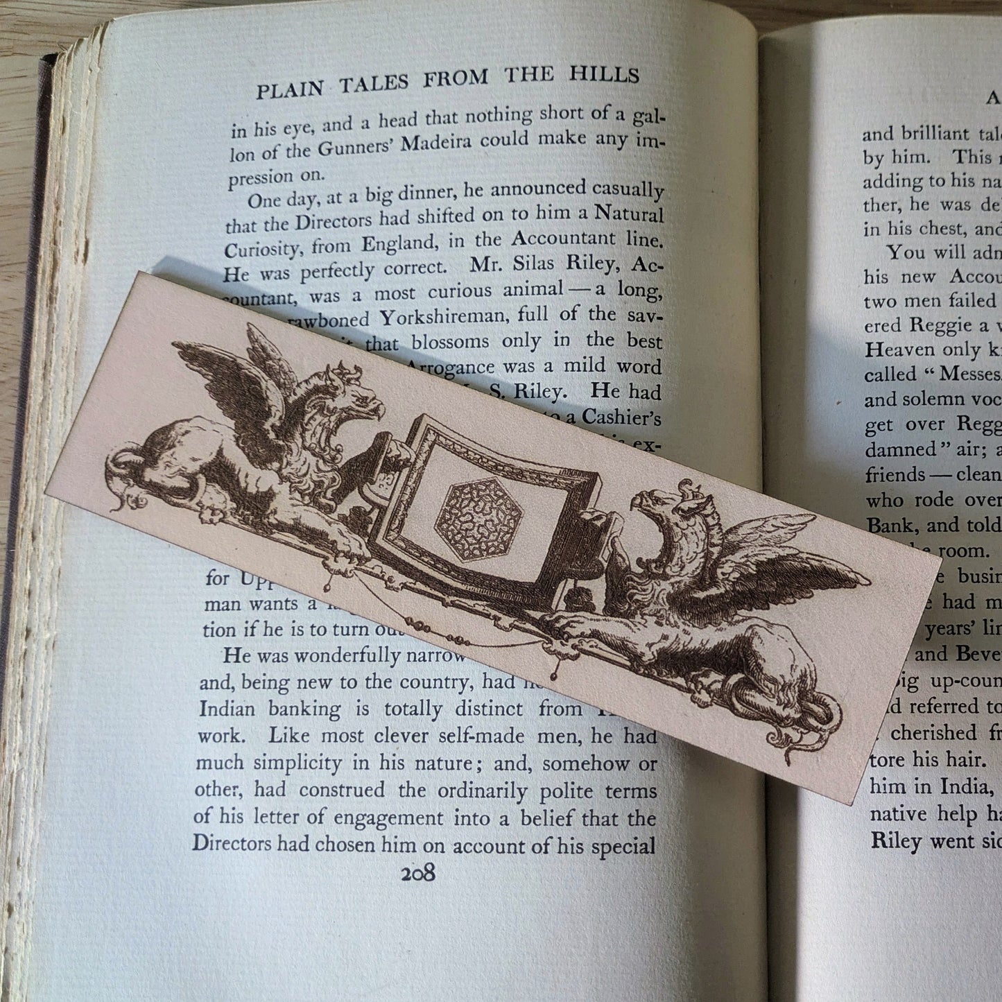 A leather bookmark with the art of 2 griffins holding a shield. 