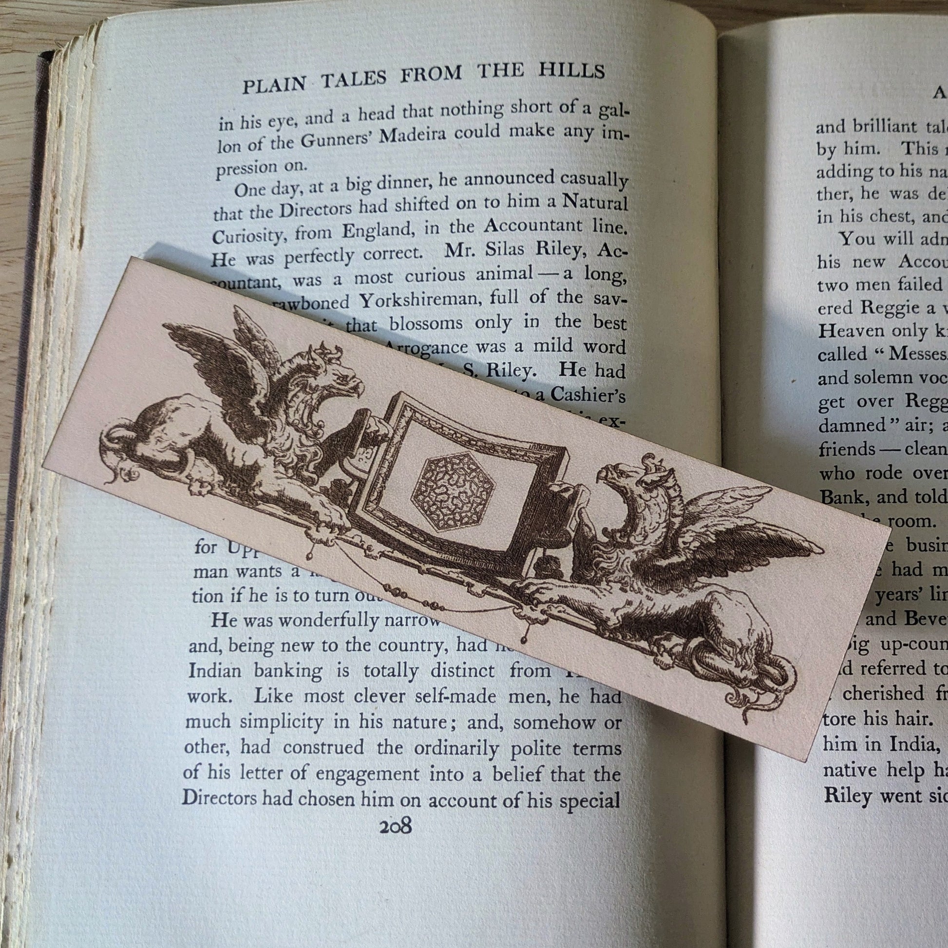 A leather bookmark with the art of 2 griffins holding a shield. 