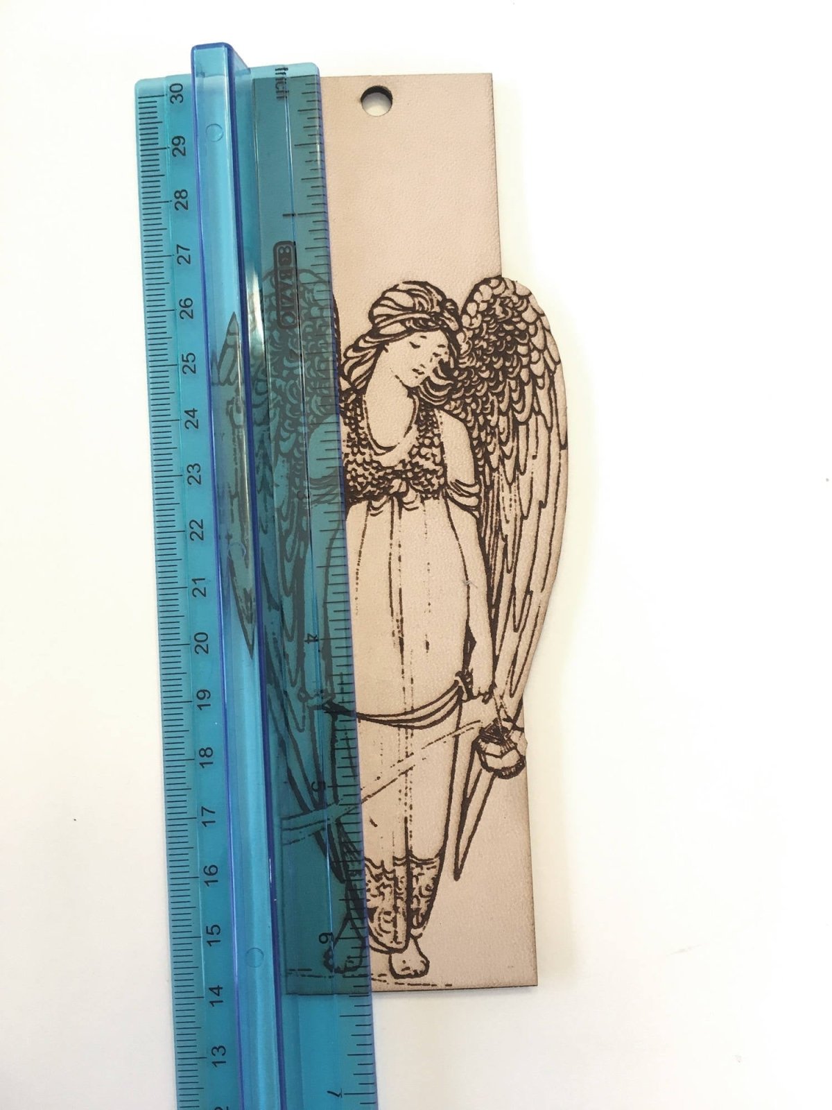 The leather angel bookmark next to a ruler to show scale.