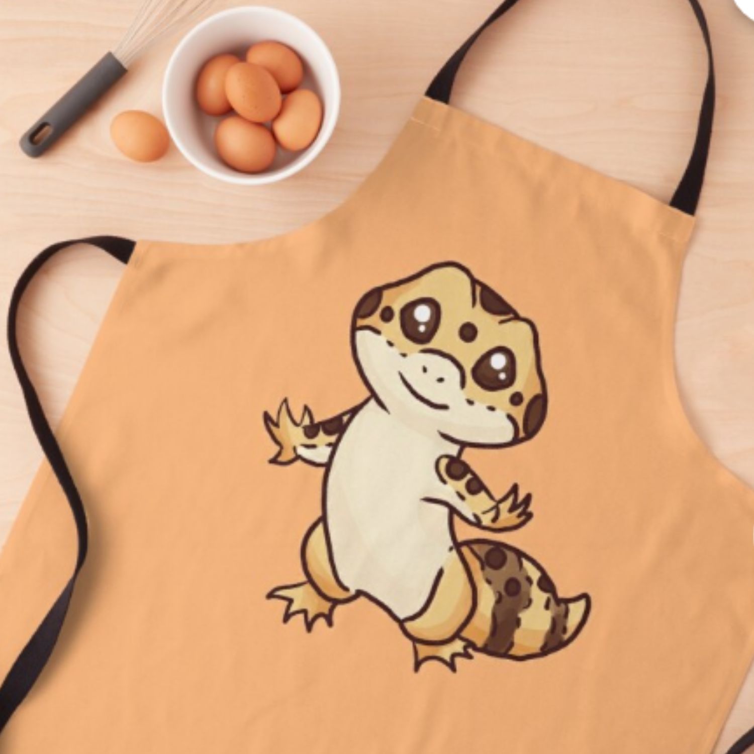 Photo of an orange apron with an adorable Chibi leopard gecko on it.