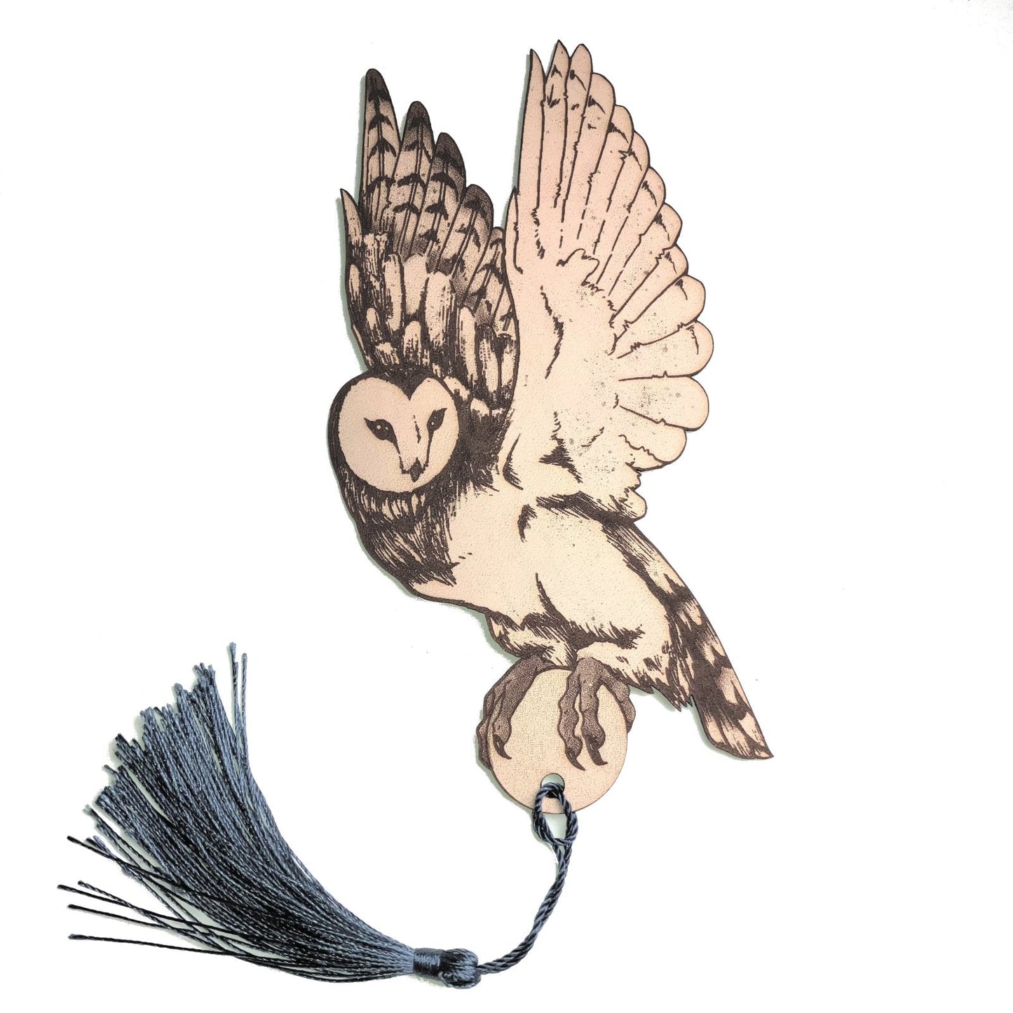 A photograph of an owl shaped leather bookmark. The bookmark has a dark grey blue tassel attached.