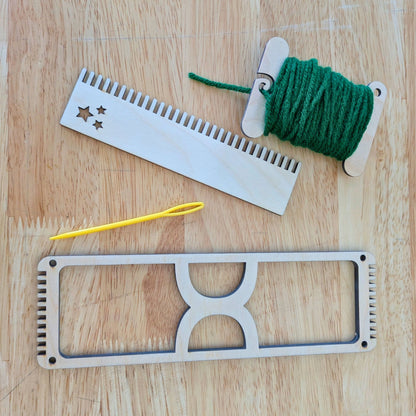 The bookmark loom next to a needle, comb and bobbin.