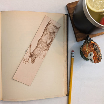 A photograph of historical caribou or reindeer leather bookmark resting on the pages of an open book. Caribou (Reindeer) Bookmark - Leather Bookmarks Raven King Crafts