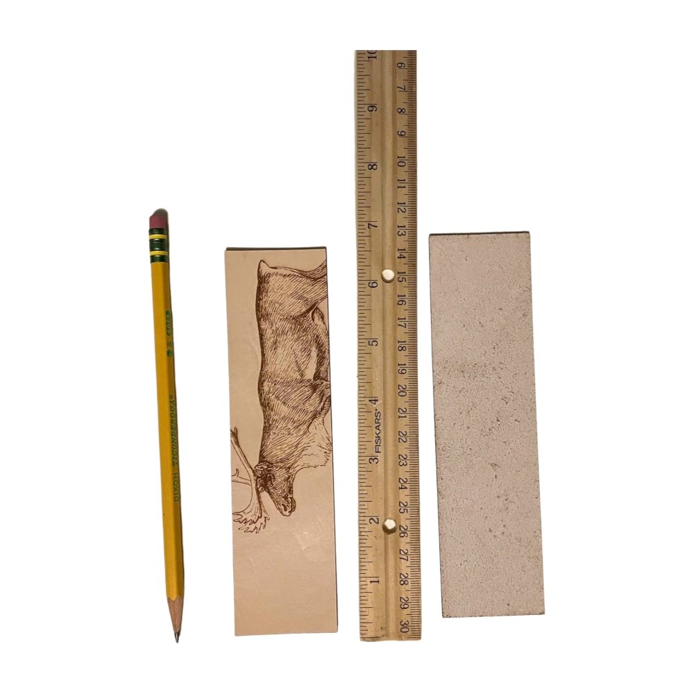 A photograph of the front of the leather bookmark and the back. The bookmarks are next to a ruler and a pencil for scale. Back photo shows the bookmark back is unfinished. Caribou (Reindeer) Bookmark - Leather Bookmarks Raven King Crafts