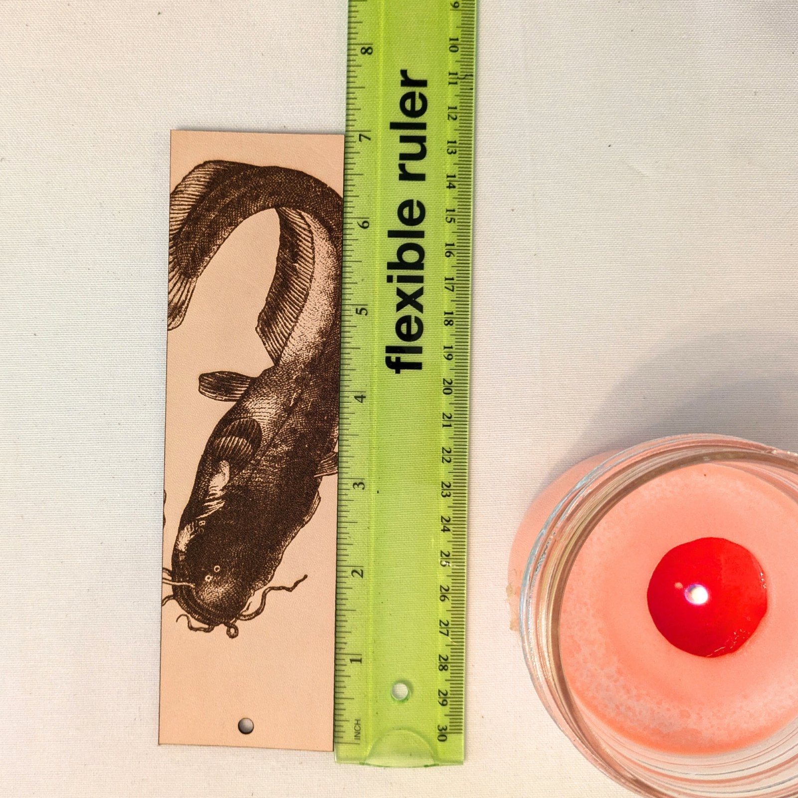 The leather catfish bookmark next to a ruler for scale. Catfish (Sheatfish) Bookmark - Leather Bookmarks Raven King Crafts