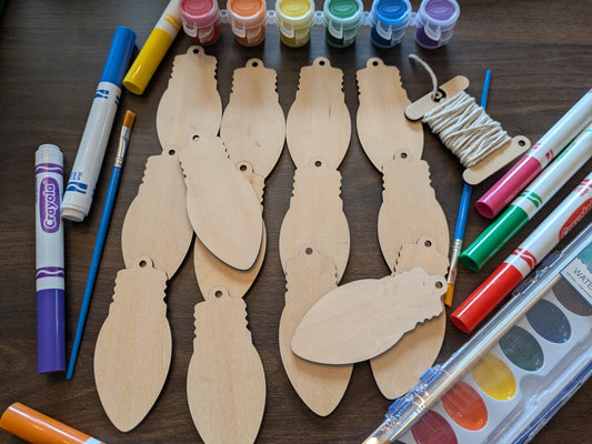 A photograph of our wooden lightbulb shaped ornament blanks. Next to them are some of the paint and marker options. Photograph from above. Christmas Lightbulb Ornaments - 14 Pack Ornament Raven King Crafts