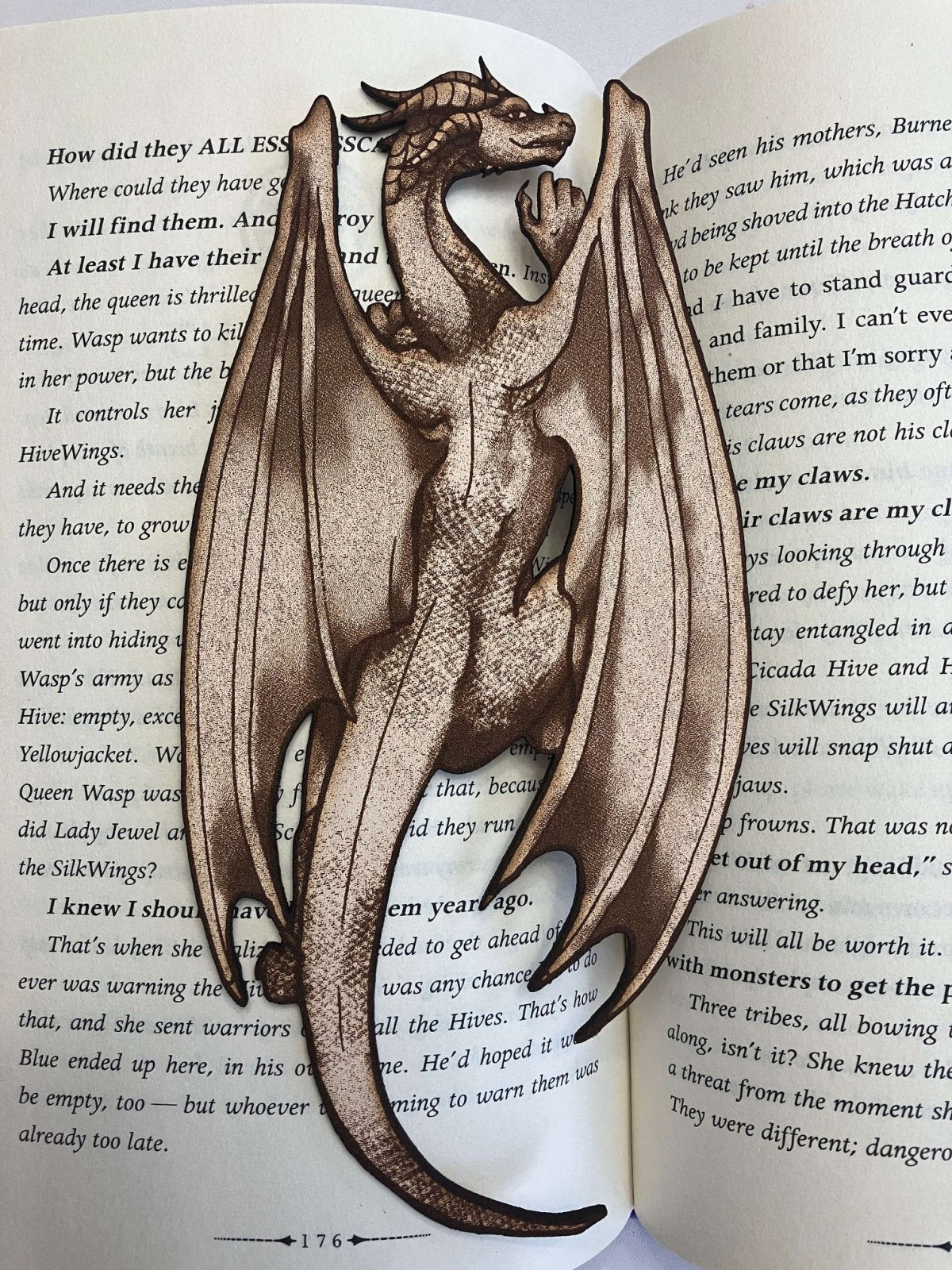 A full length photo of the leather dragon bookmark. The bookmark looks like a dragon climbing on the pages of a book.