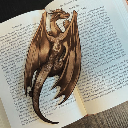 A photograph of the dragon bookmark resting on the pages of an open book. The bookmark is shaped like the a dragon.