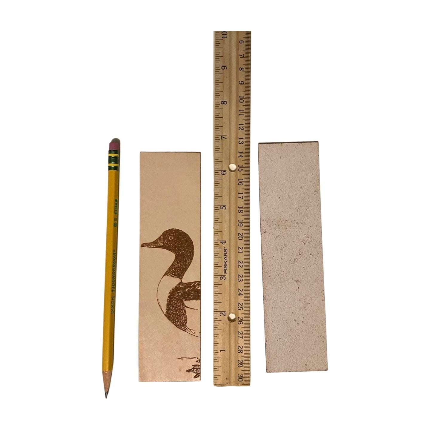 The duck bookmark next to a ruler for scale. It also shows that the back in unfinished. Common Shelduck Bookmark - Leather Bookmarks Raven King Crafts