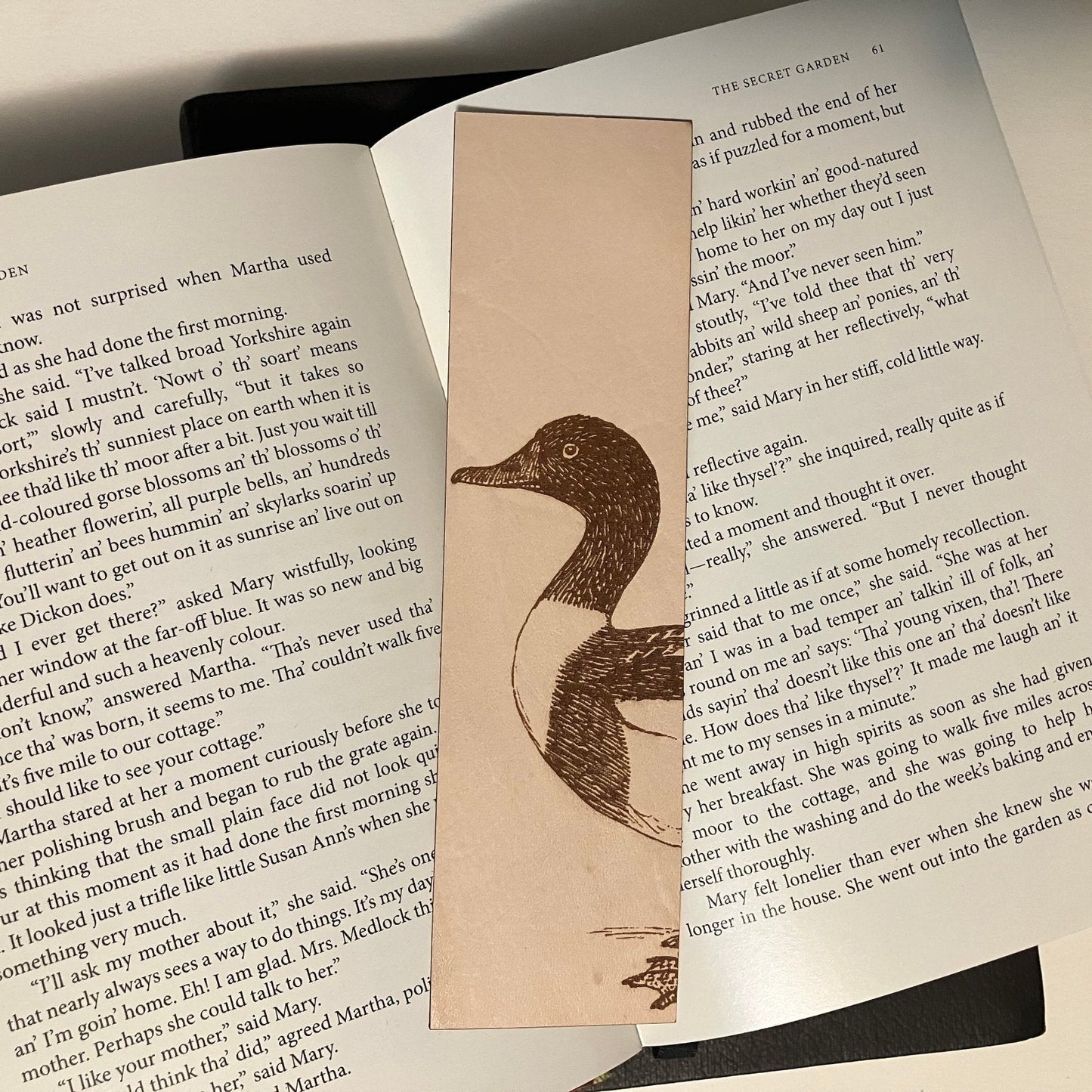 A photograph of a shelduck bookmark resting on the pages of an open book.