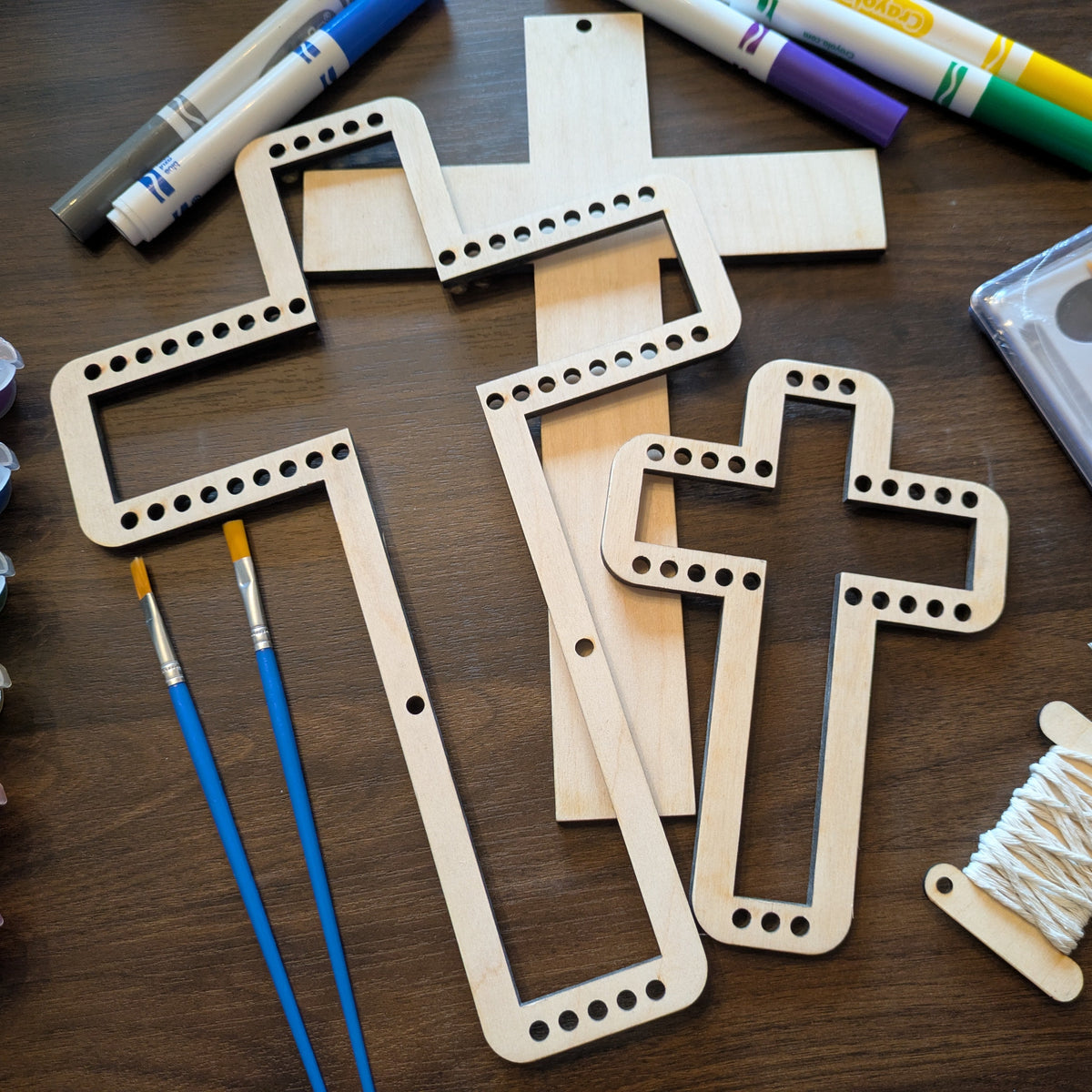A photograph of our wooden loom set. It shows 2 cross shaped looms and one cross shaped blank.