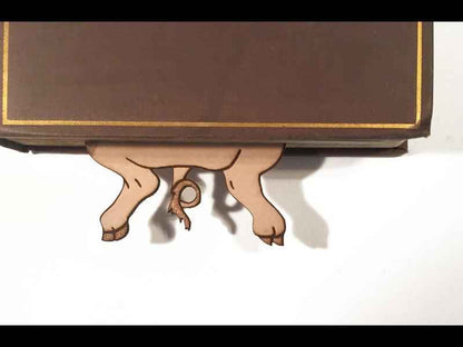 The feet of our cute bookmark poking out from the bottom of a book. Cute Leather Pig Bookmark Bookmarks Raven King Crafts