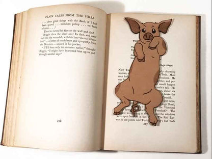Our adorable pig bookmark resting on the pages of an open book. Cute Leather Pig Bookmark Bookmarks Raven King Crafts