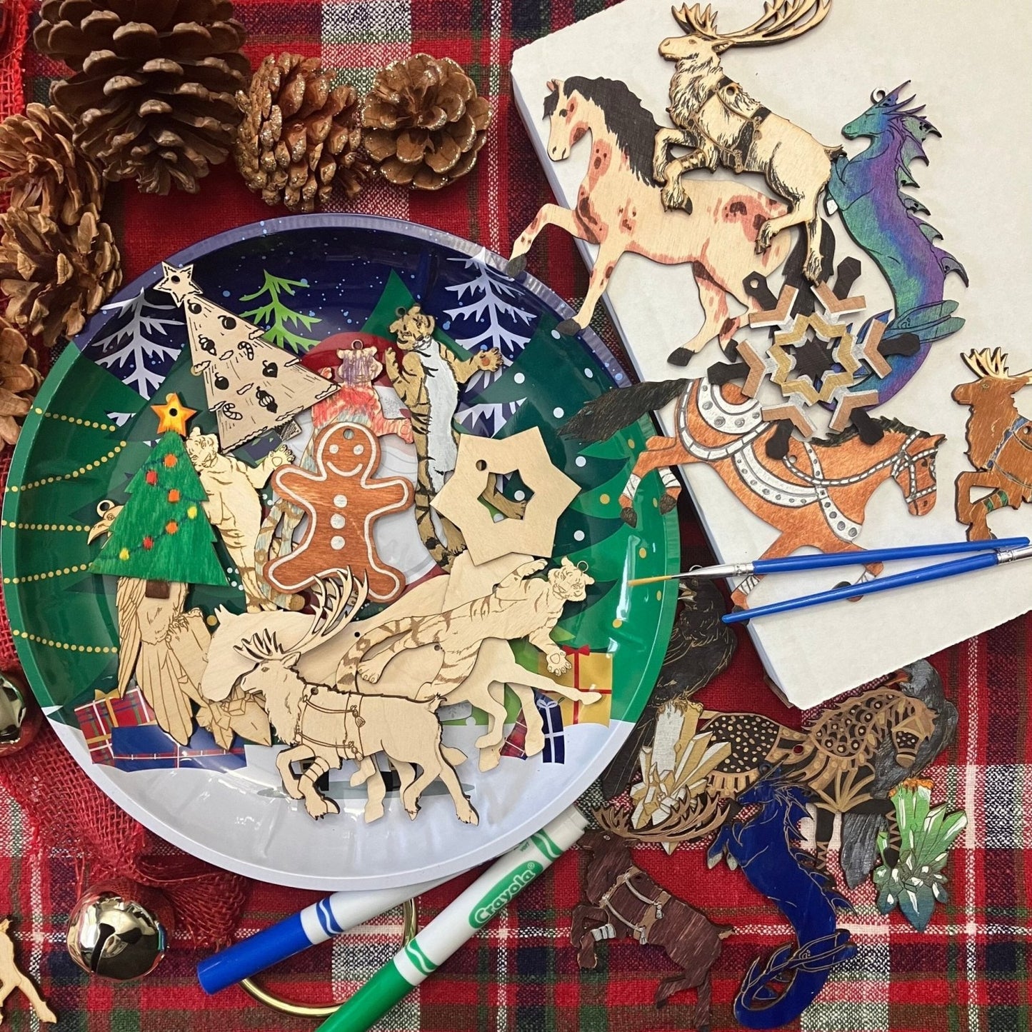 A photograsph of finished and unfinished ornaments. The ornaments are resting on a Christmas colored table cloth and a Christmas themed plate.