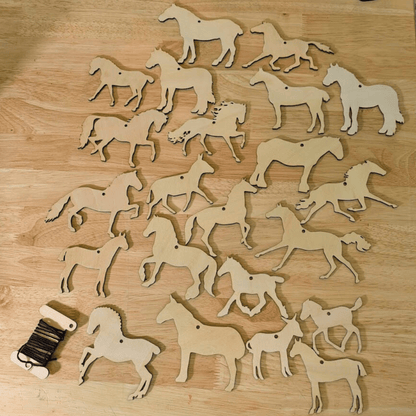 A photograph of both sets of wooden horse, donkey and mule ornaments. For a total of 20 unique horse cutouts. In the lower left corner is a bobbin of string, the color of string will vary. DIY Wooden Horse Ornament Kit - 10 Unique Horse Shapes per Set - 20 total! Art & Crafting Materials Raven King Crafts