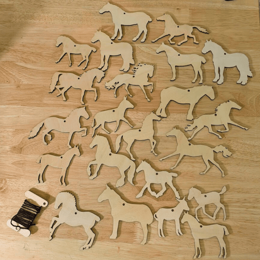A photograph of both sets of wooden horse, donkey and mule ornaments. For a total of 20 unique horse cutouts. In the lower left corner is a bobbin of string, the color of string will vary. DIY Wooden Horse Ornament Kit - 10 Unique Horse Shapes per Set - 20 total! Art & Crafting Materials Raven King Crafts
