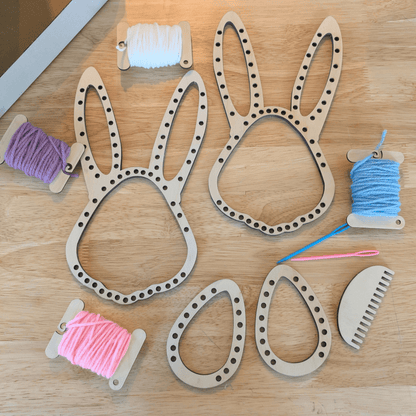 A photograph of the Easter Loom set, including 2 rabbit head shaped looms, 2 egg shaped loos, a comb, 2 needles and 4 spools of spring colored yarn. Easter Bunny and Egg Loom Kit Art & Craft Kits Raven King Crafts