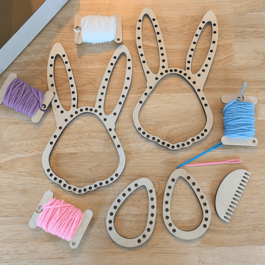A photograph of the Easter Loom set, including 2 rabbit head shaped looms, 2 egg shaped loos, a comb, 2 needles and 4 spools of spring colored yarn. Easter Bunny and Egg Loom Kit Art & Craft Kits Raven King Crafts