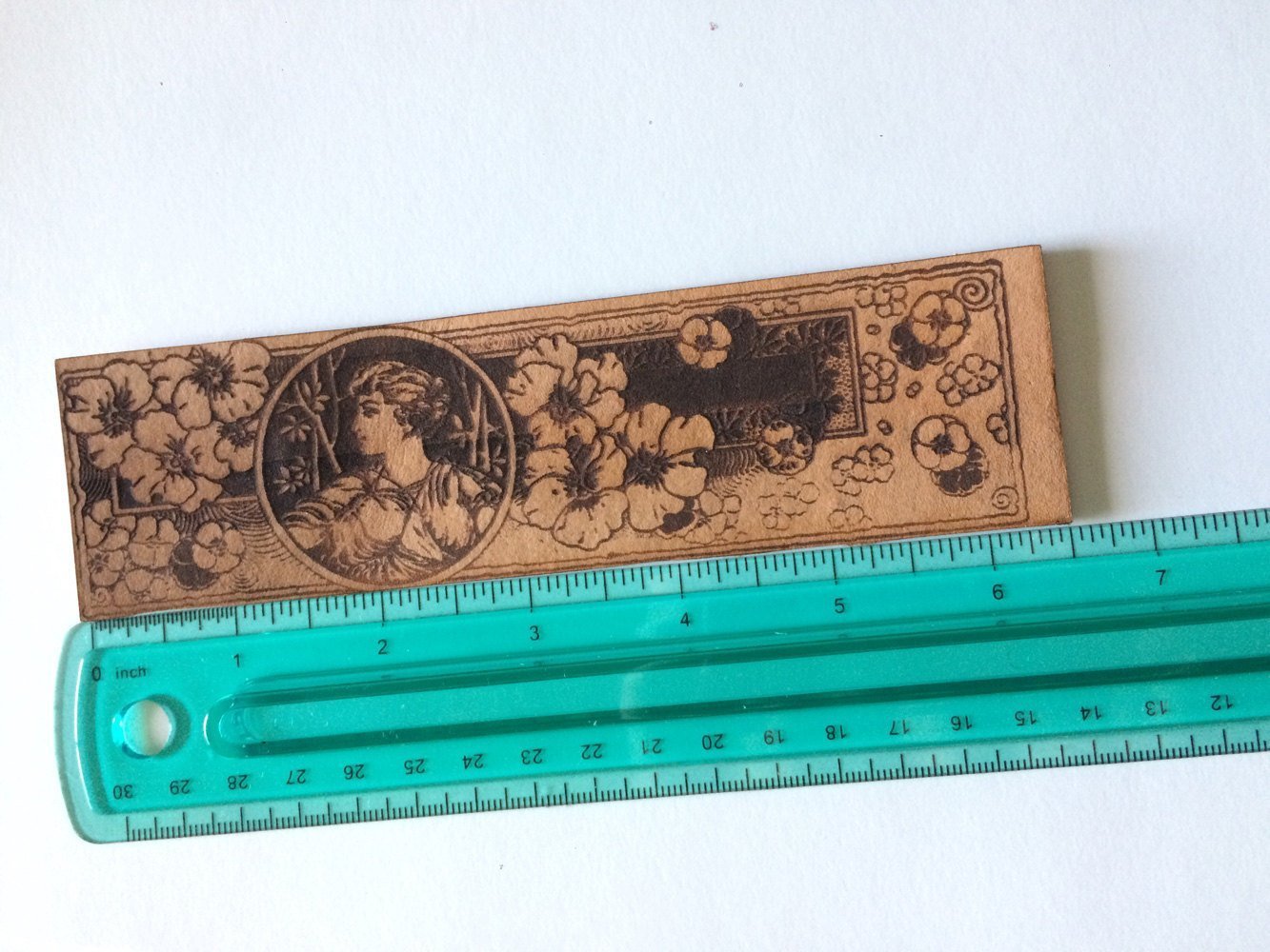 the bookmark of a Greek woman and wildflowers against a ruler