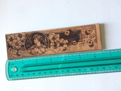 the bookmark of a Greek woman and wildflowers against a ruler