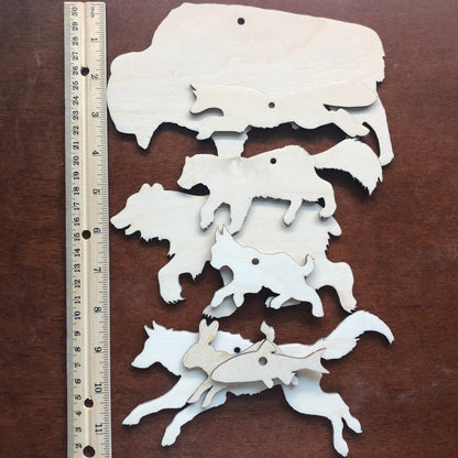 Each of the forest wood cutouts next to a ruler for scale. Top to bottom: bison, fox, wolverine, bear, bobcat, fish, rabbit and wolf.