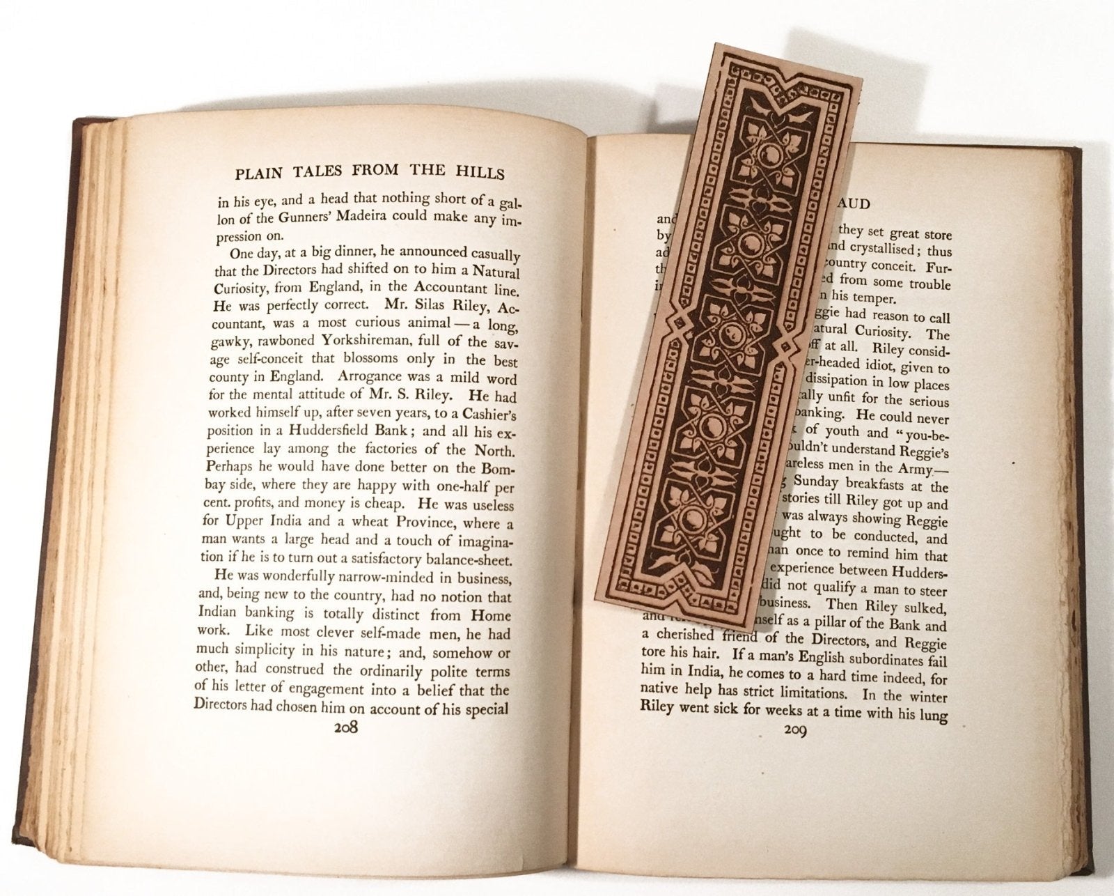 A photo of the geometric decorative bookmark resting on the pages of an open book., Geometric Decorative Bookmark - Leather Bookmarks Raven King Crafts