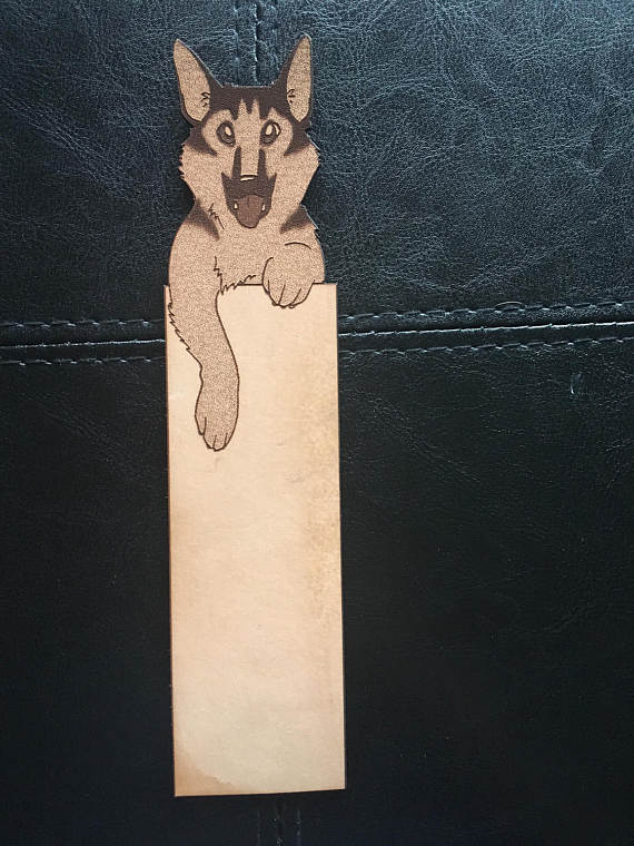 A photograph of a leather bookmark with the art of a GSD at the top and a blank space under it for adding a message or name.