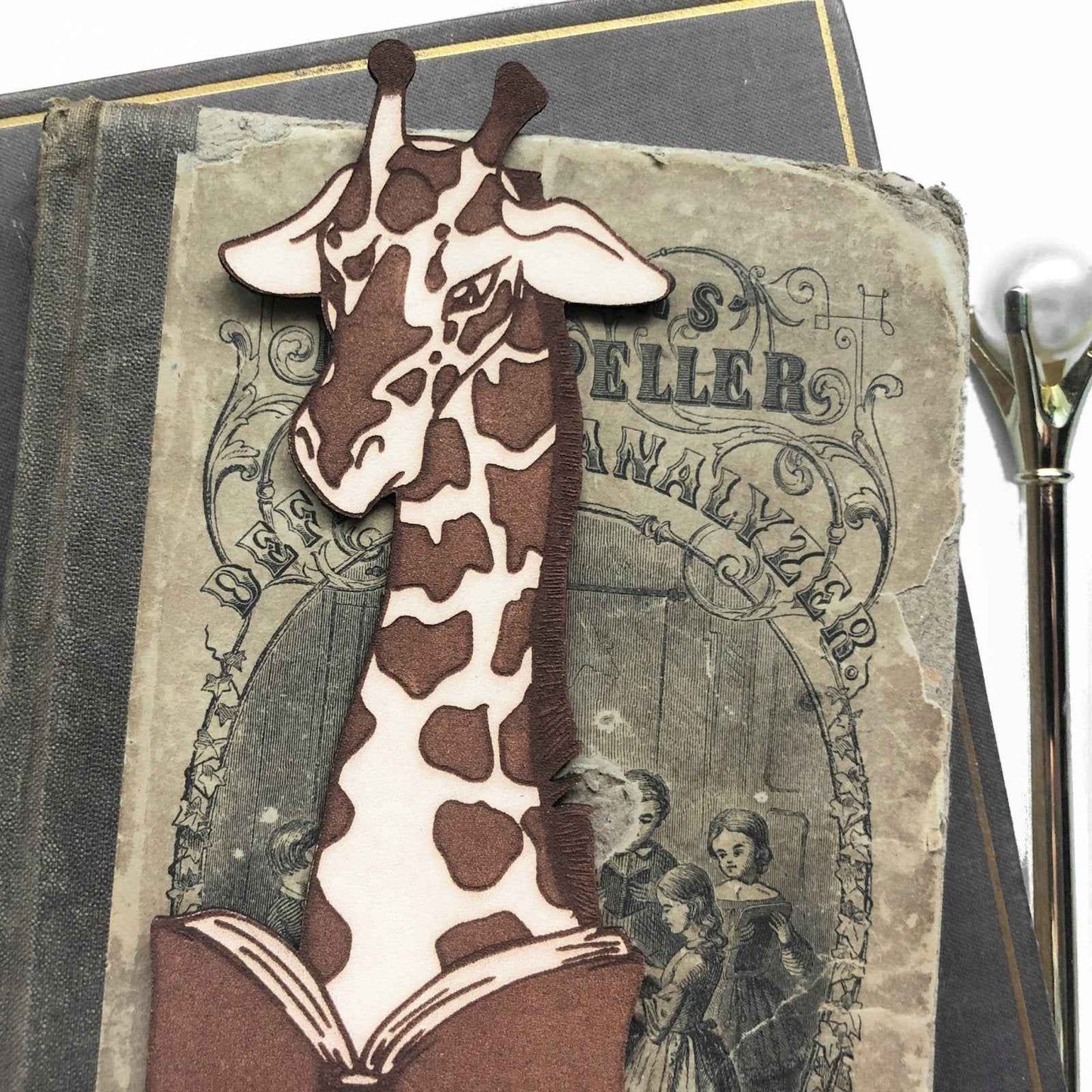 A leather bookmark shaped like a giraffee reading a book. Great Book lover gift. Giraffe Reading Leather Bookmark - Quirky Book-Lover Gift Bookmarks Raven King Crafts
