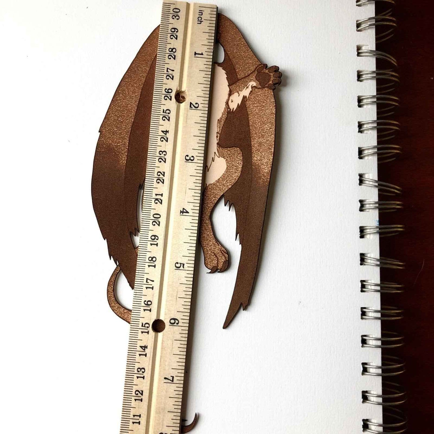 The Griffyn bookmark next to a ruler for scale. Griffin Bookmark - Leather | Wonderful Fantasy Beast Gift Bookmarks Raven King Crafts