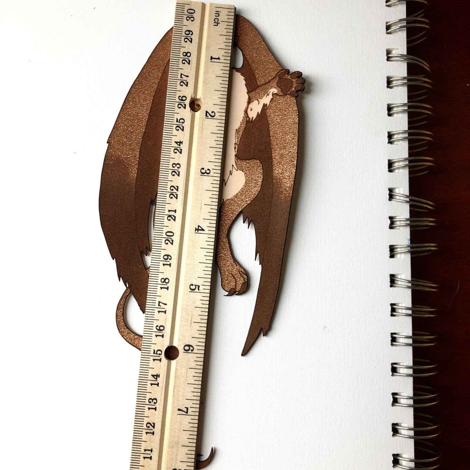 The Griffyn bookmark next to a ruler for scale. Griffin Bookmark - Leather | Wonderful Fantasy Beast Gift Bookmarks Raven King Crafts