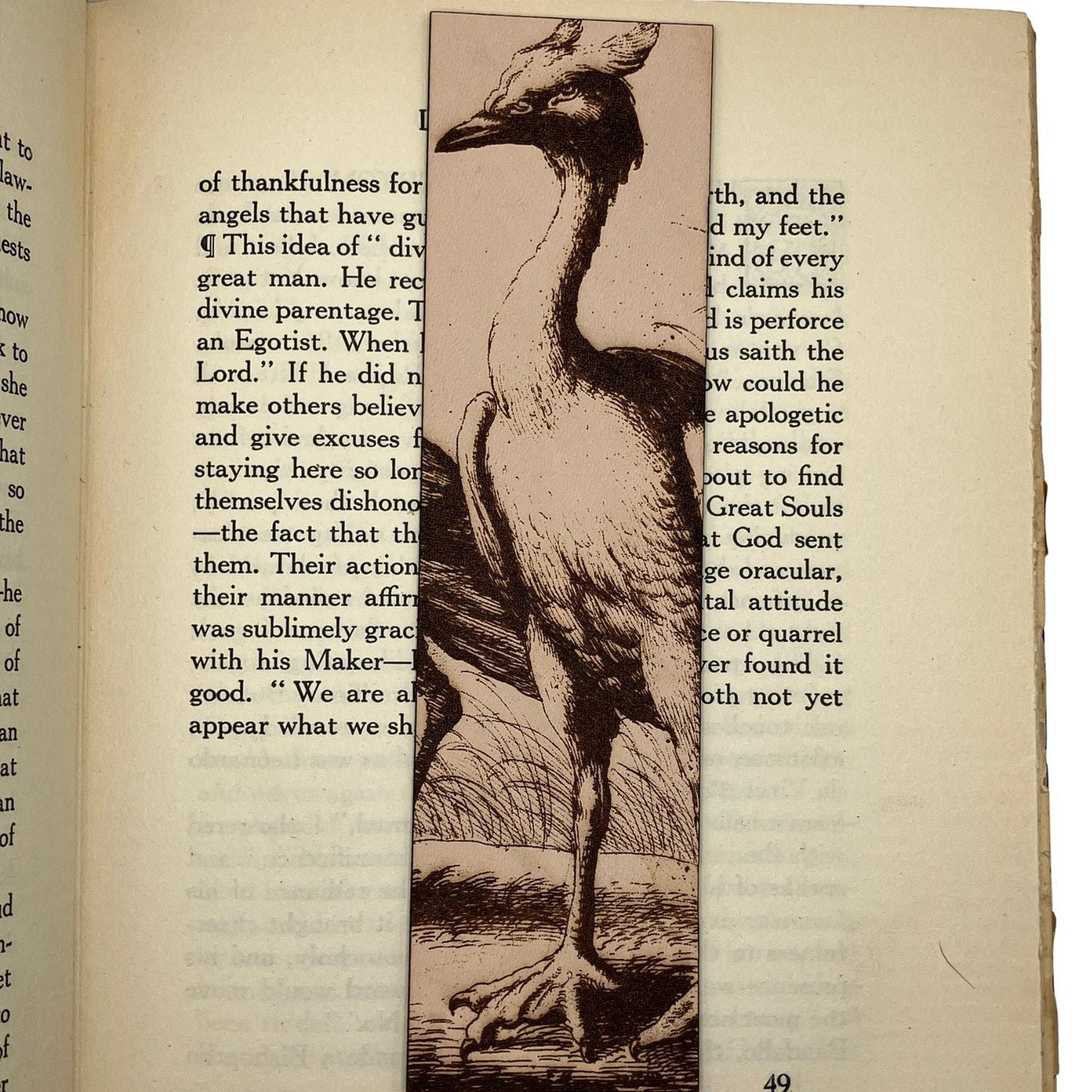 A leather bookmark with a heron engraved on it. The bookmark is resting on the pages of an open book.