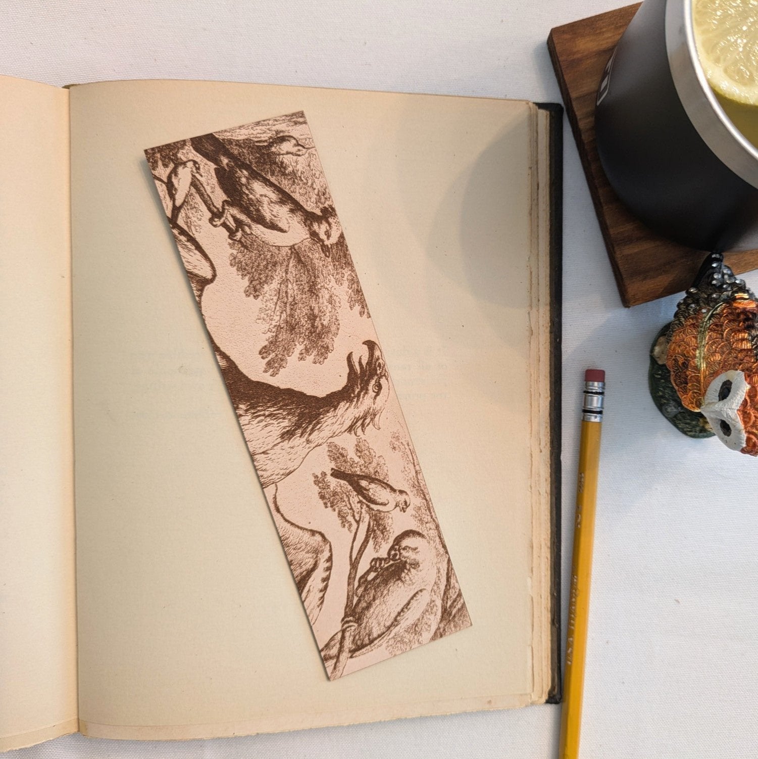 A photograph of the historical birds bookmark. The bookmark is engraved with the art of several birds on it includin ga parrot and an eagle. Historical Birds Bookmark - Leather Bookmarks Raven King Crafts
