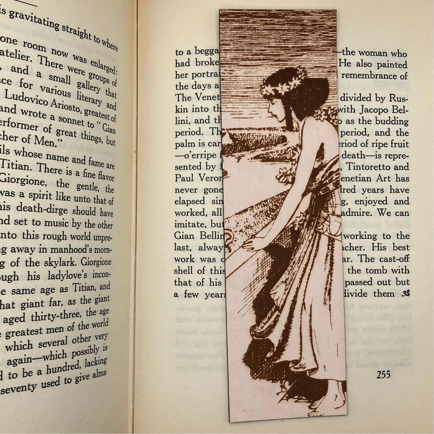 A leather bookmark with the historical art of an Egyptian woman engraved on it. The bookmark is resting on the pages of an open book. Historical Egyptian Woman Bookmark - Leather Bookmarks Raven King Crafts