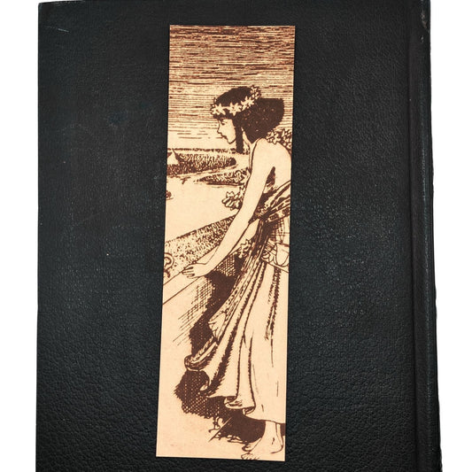 The Egyptian woman bookmark resting on the closed cover of an old leather book. Historical Egyptian Woman Bookmark - Leather Bookmarks Raven King Crafts