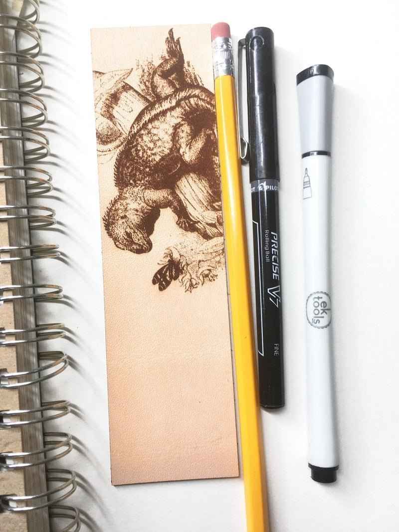 A leather bookmark engraved with the antique art of a iquana. Historical Leather Iguana Bookmark Bookmarks Raven King Crafts